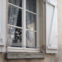 a window with white shutters and curtains
