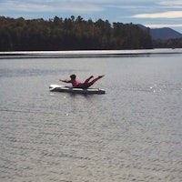 a woman is floating on a surfboard in a lake