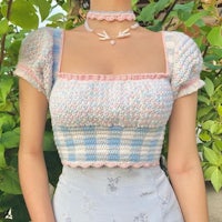 a woman wearing a crocheted top and skirt