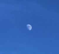the moon is seen through a clear blue sky