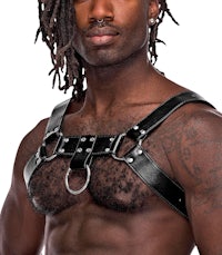 a man with dreadlocks wearing a black leather harness
