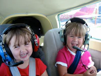 two young girls in a plane wearing headsets