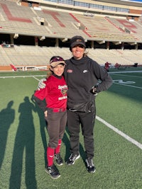 a woman and a young girl posing for a picture on a baseball field