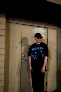 a man in a t - shirt standing in front of a door