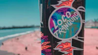 a pole with a colorful sticker on it next to a beach