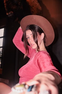 a woman wearing a cowboy hat in front of a bison