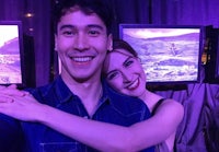 a man and woman posing for a selfie in front of a television