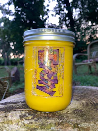 a jar of yellow candle sitting on a wooden stump