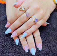 a woman's hands with pink and blue nails and rings