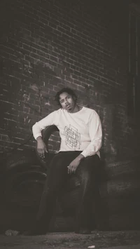 a man sitting on a tire in front of a brick wall