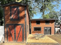 a small log cabin with a deck and patio