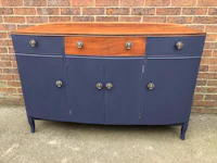 a blue painted sideboard with wooden drawers