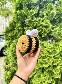 a person holding a crocheted bee toy