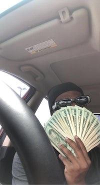 a man sitting in the driver's seat of a car with money in his hands