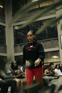 a woman in a red hoodie walking down the runway