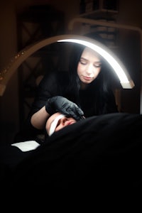 a woman getting a facial treatment in a dark room