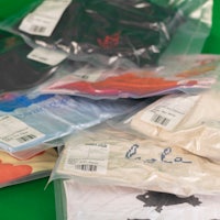 a group of t - shirts in plastic bags on a green background