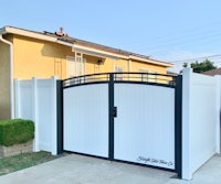 a white fence with a black gate in front of a house