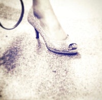a woman in a pair of high heeled shoes holding a purse