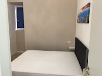 a small bedroom with a white bed and a painting on the wall