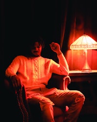 a man sitting in a chair next to a lamp