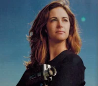 a woman holding a camera in front of a blue sky