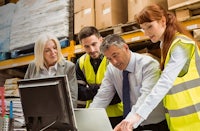a group of people looking at a laptop in a warehouse