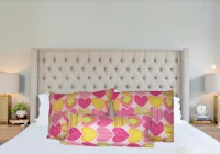 a bed with pink and yellow pillows on it