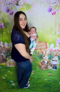 a woman holding a baby in front of an easter backdrop