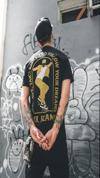 a man wearing a black t - shirt with graffiti on it