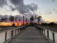 a wooden boardwalk leading to a lake at sunset
