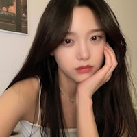 a girl with long black hair posing with her hand on her face