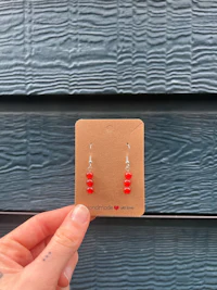 a person holding a card with red glass beads on it