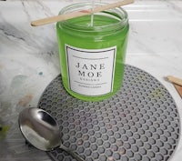 a jar of green candle with a spoon on top