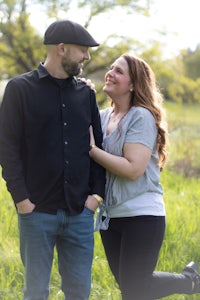 a man and woman are standing in a grassy field