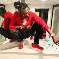 a man in a red shirt is crouching in front of a mirror