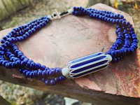 a blue and white beaded necklace on a rock