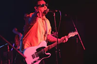 a man holding a guitar in front of a microphone