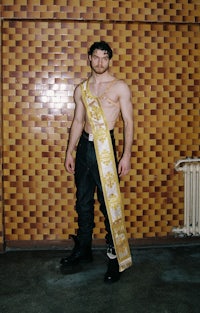 a man with a sash in front of a brick wall