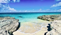 a beach with a rocky shore and clear blue water