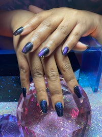 a woman's hand with purple and blue nails and a crystal
