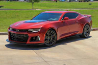 a red chevrolet camaro parked in a parking lot