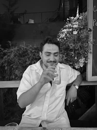 a man sitting at a table drinking a glass of wine