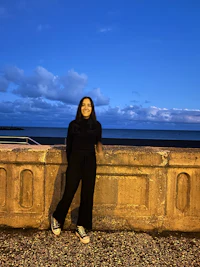 a woman leaning against a wall at dusk