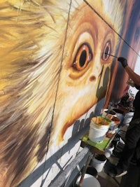 a man painting a mural of a monkey on the side of a building