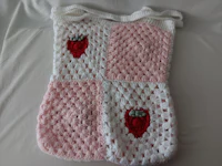a pink and white crocheted blanket with a strawberry on it