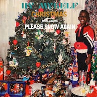 a young boy standing in front of a christmas tree