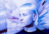 a woman with blond hair in front of a blue flower
