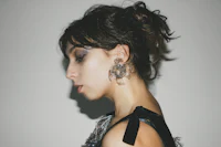 a woman in a black dress with silver earrings