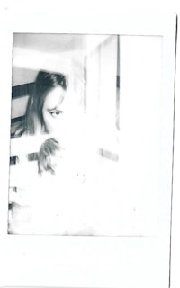 a black and white photo of a woman looking out of a window